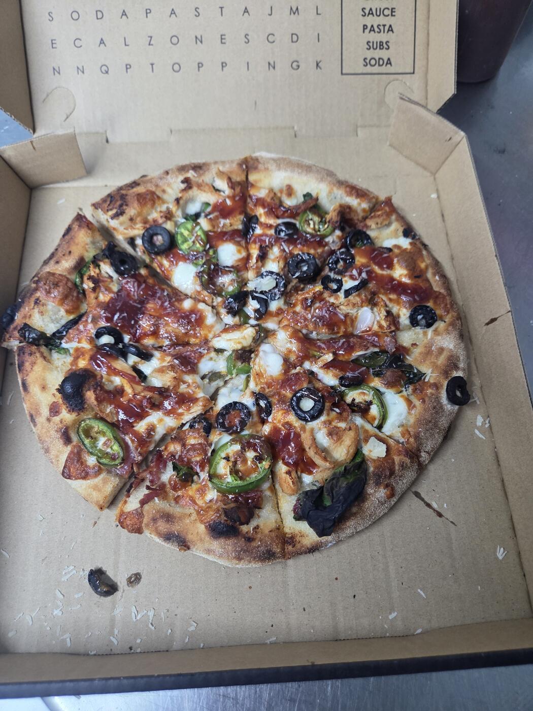 Garlic chicken pizza with chicken, jalapeño, black olive, and a red sauce