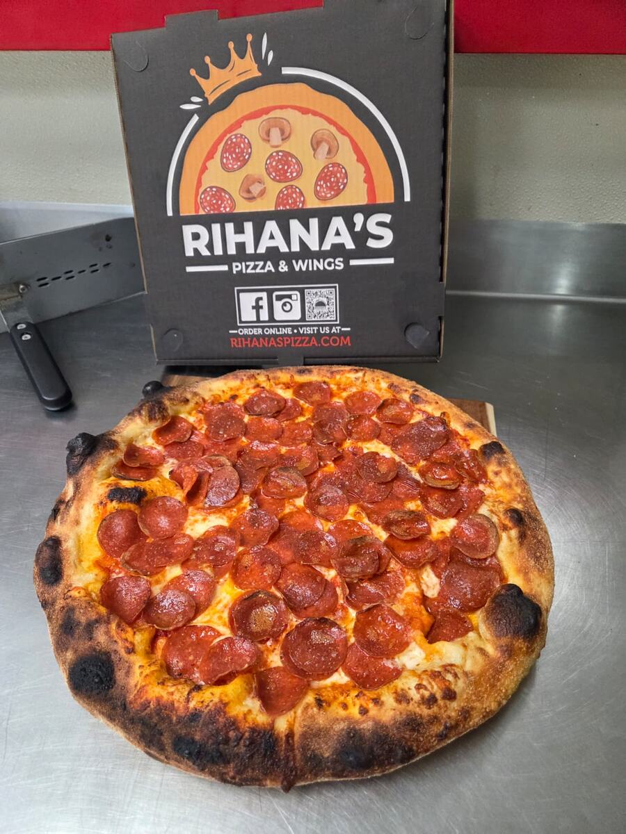 Pepperoni pizza with a blistered crust, Rihana's box standing behind it