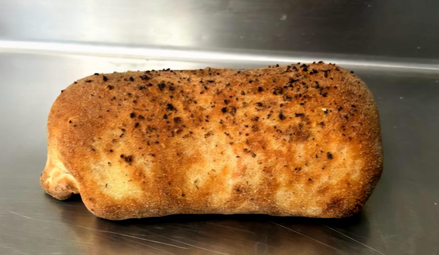 A golden herb-topped pizzoli on the prep table