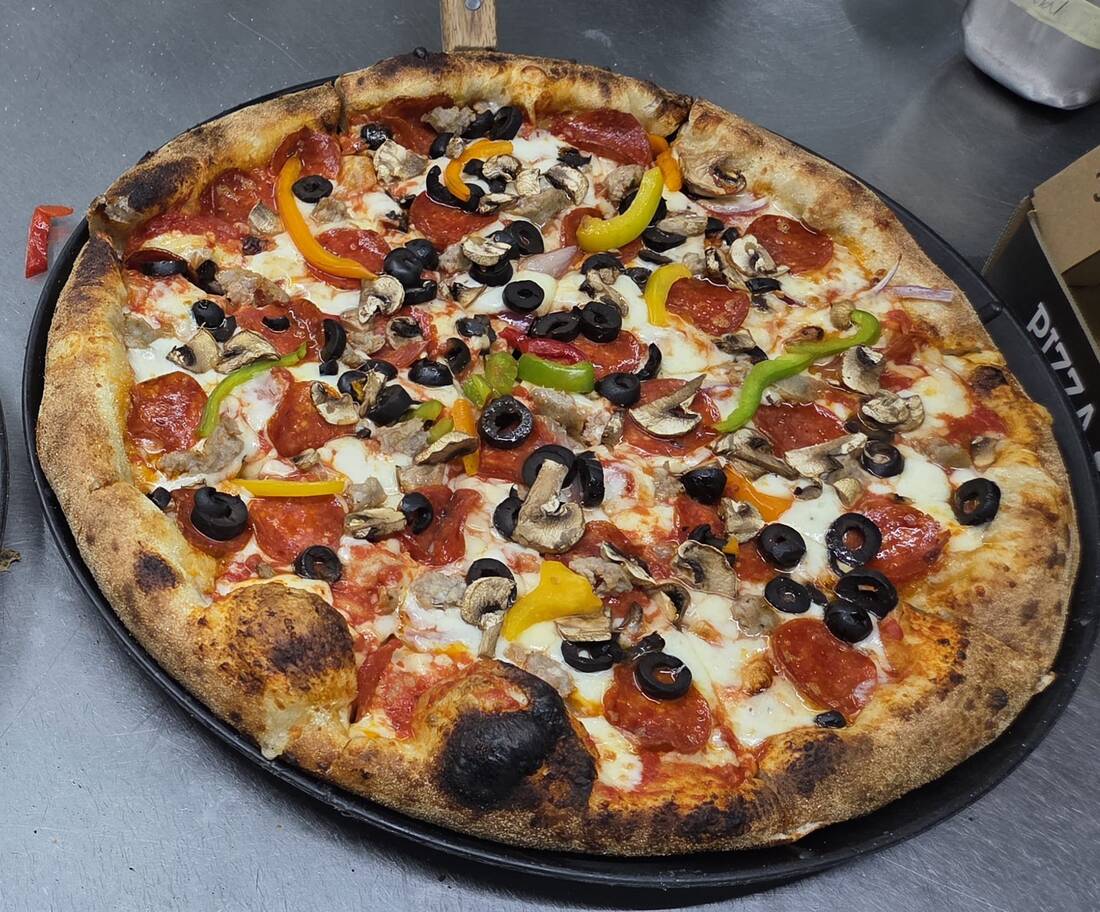Loaded pizza with pepperoni, sausage, mushrooms, olives, peppers, and onion