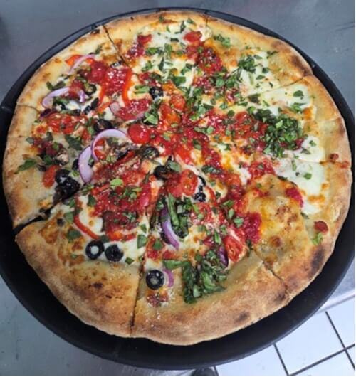 Veggie pizza with olives, onion, peppers, and fresh herbs